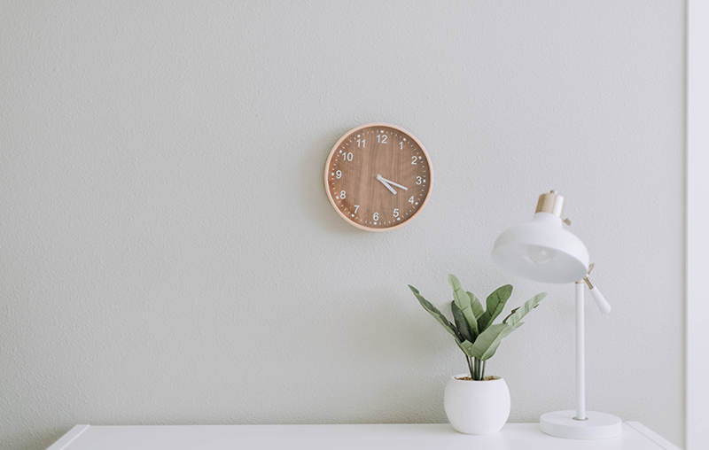 simple white desk on a white wall with
              a plant on the far right side